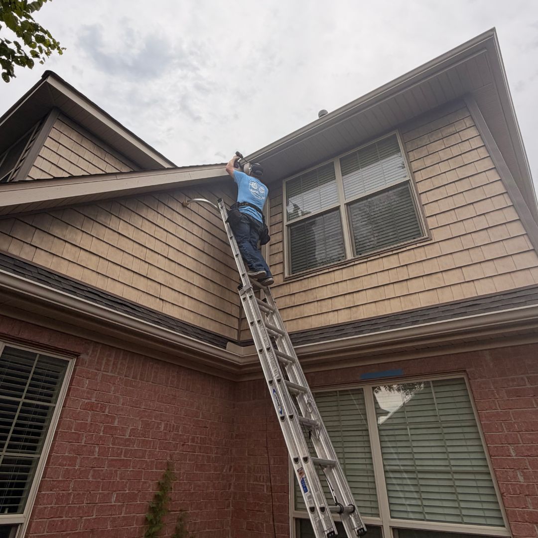 Working the gutter line from the ladder on a two-story home